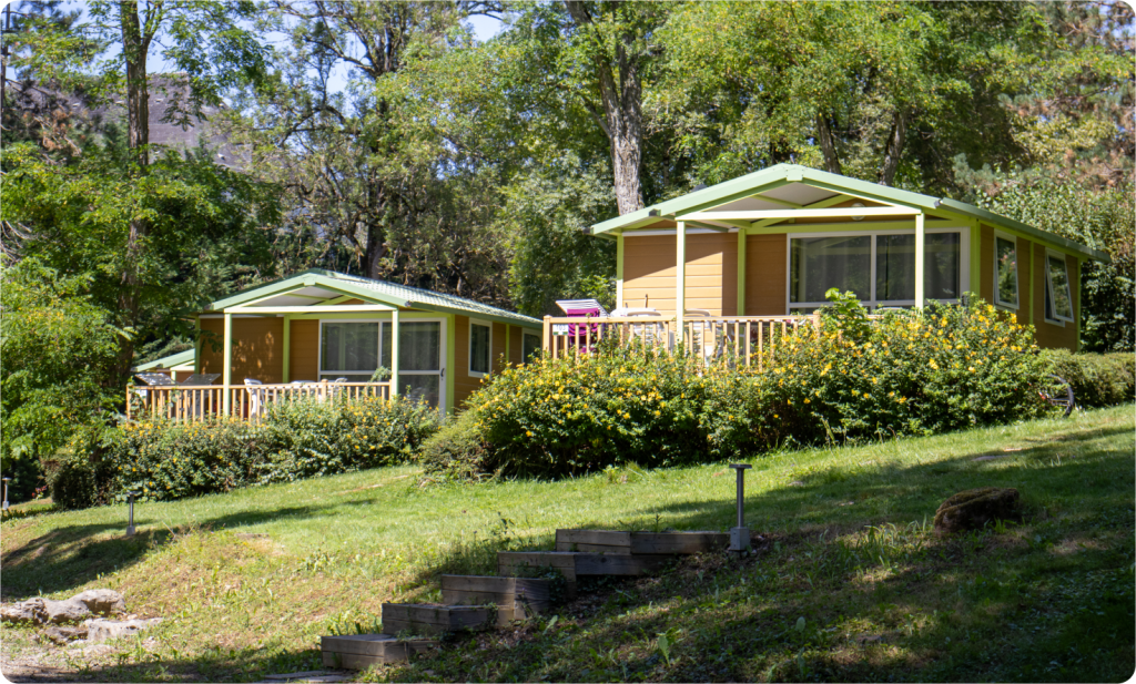 “Chalets 25 m² avec terrasse, nichés dans un cadre verdoyant, au Camping Parc d’Audinac les Bains, parfaits pour 5 personnes.”