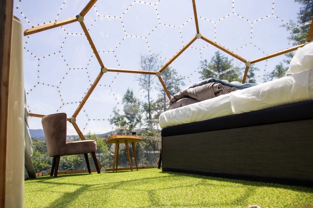 Vue intérieure du Géopod avec lit double et fauteuils face aux montagnes en Ariège