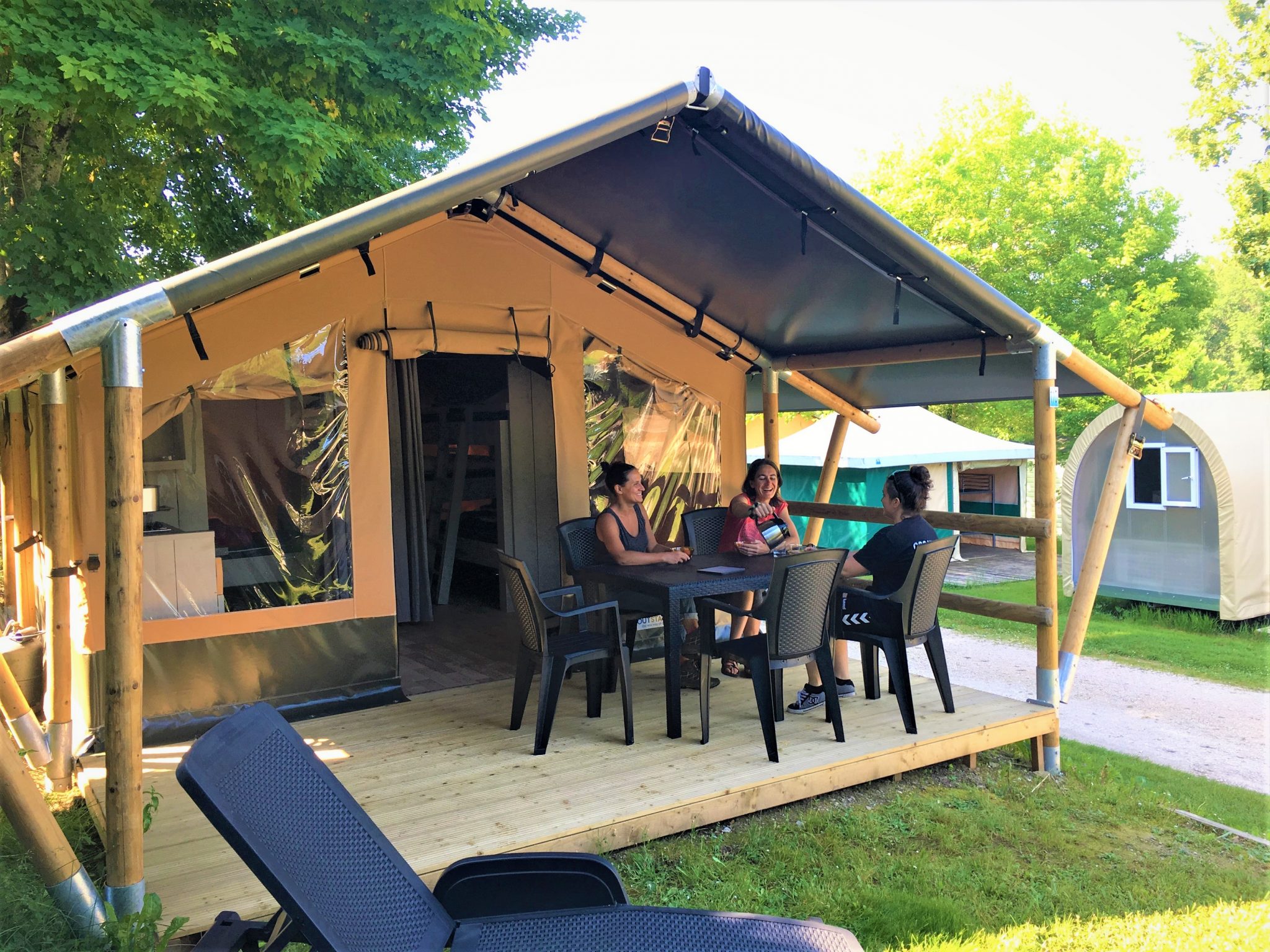 Famille profitant de la terrasse d’une Tente Lodge au Camping Parc Audinac-les-Bains