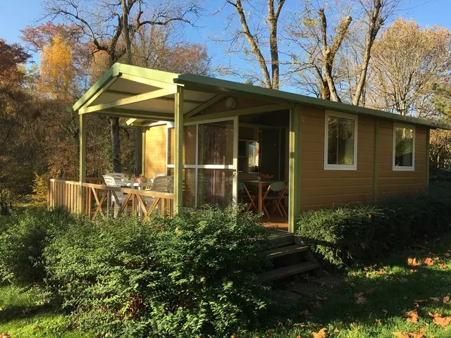 Chalet Gitotel Moréa climatisé avec terrasse couverte en bois, entouré de verdure au Camping Audinac les Bains en Ariège