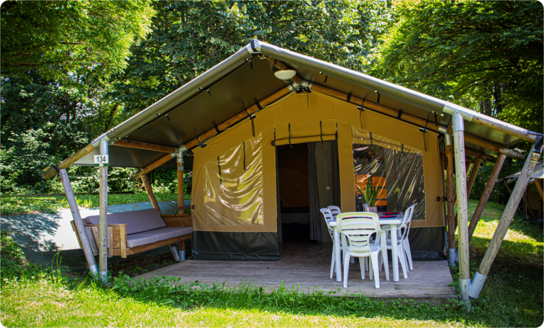 Tente lodge et sa terrasse aménagée au milieu de la verdure